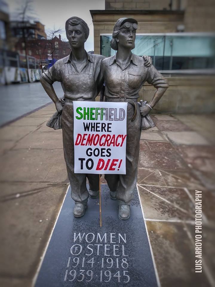 Women of Steel statue with placard saying "Sheffield, where democracy goes to die!"