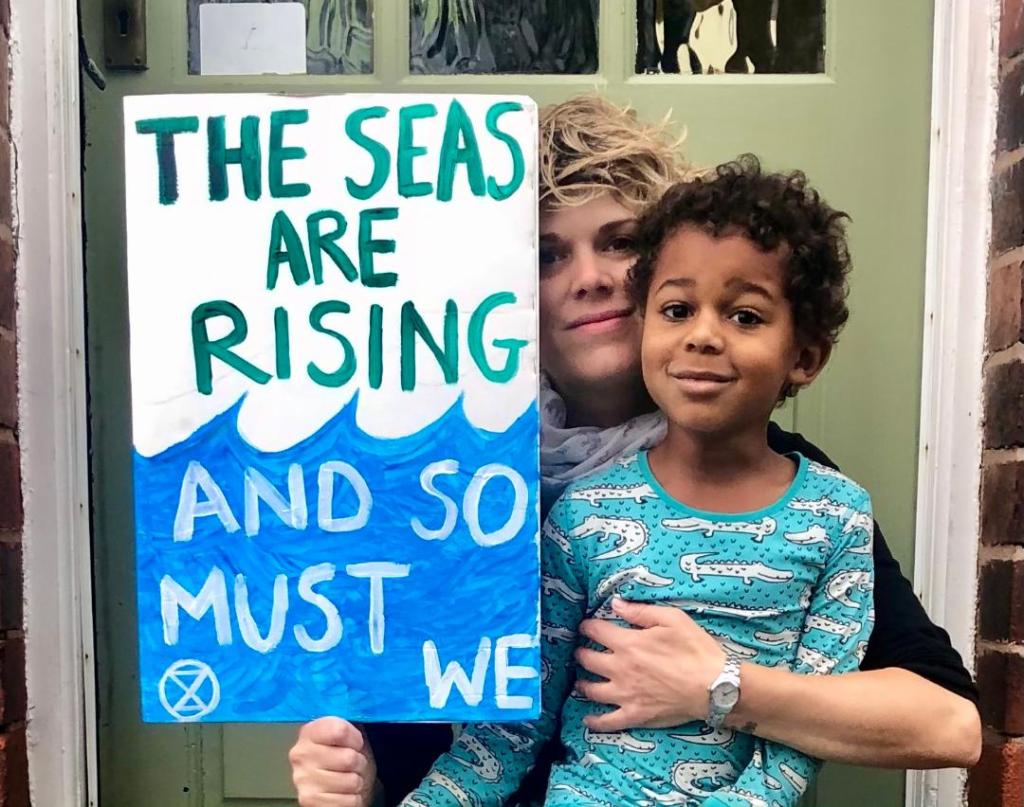 Hazel and her son with a placard which reads "The seas are rising and so must we".