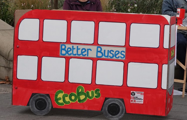 A cardboard bus with adverts Better Buses" and "Eco Bus"