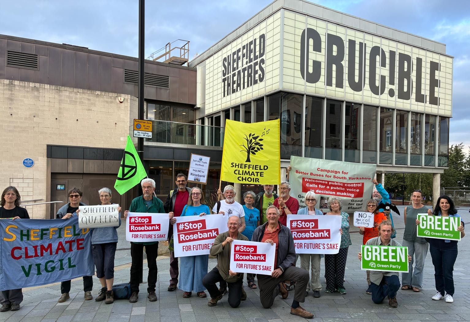 Stop Rosebank campaigners outside the Crucible, Sheffield with signs saying Stop Rosebank, an XR flag, Tell the Truth Sheffield Says no to Rosebank, Green Party, Better Buses South Yorkshire.